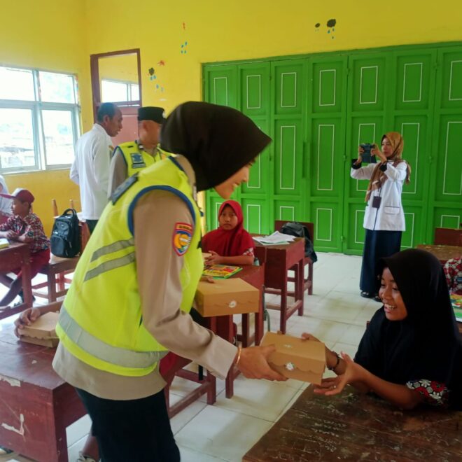 Bhabinkamtibmas Bripka Corry Syamsuarni membagikan makanan bergizi kepada siswa/wi SD Negeri Sukoharjo.