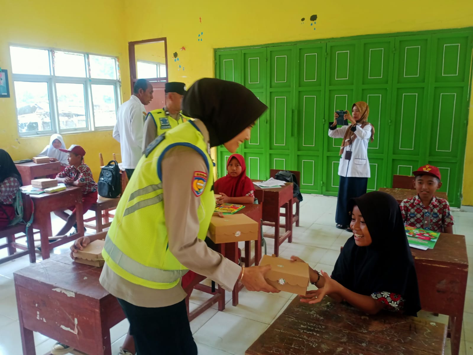 Bhabinkamtibmas Bripka Corry Syamsuarni membagikan makanan bergizi kepada siswa/wi SD Negeri Sukoharjo.
