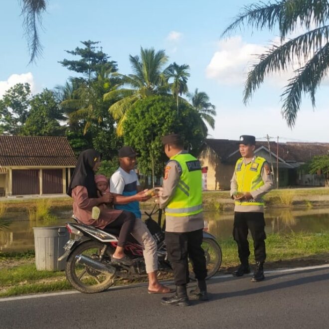Personel Polsek BMT bagi-bagi takjil ke pengendara di Jalan Raya Belitang, depan Mapolsek BMT.