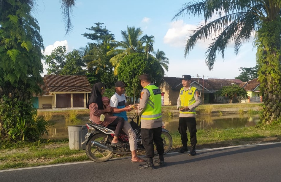 Personel Polsek BMT bagi-bagi takjil ke pengendara di Jalan Raya Belitang, depan Mapolsek BMT.