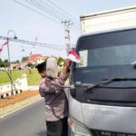 Personel Polsek Buay Madang Timur (BMT) memasangkan bendera merah putih pada tiap kendaraan yang melintas.