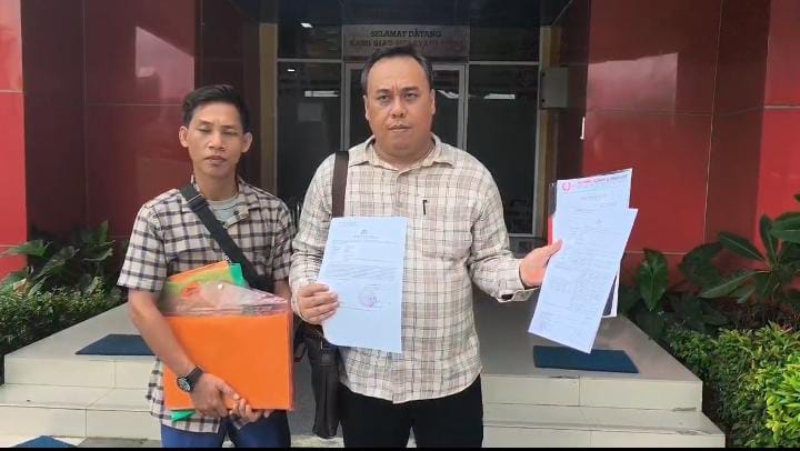 Saat  korban Dedi Irawan yang didampingi tim penasihat hukumnya Achmad Azhari SH menunjukkan surat tanda penerimaan laporan di SPKT Polda Sumsel , Jumat (13/3/2026)