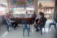 Anggota Bhabinkamtibmas Polsek Buay Madang Timur Brigadir Rusendi bersama Babinsa Serda Adirin saat berdialog dengan tokoh masyarakat dan perangkat Desa Berasan Mulya, OKU Timur. 