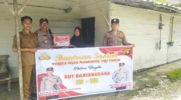 Kapolsek Buay Madang Timur, IPTU Swisspo, (kedua dari kiri), menyerahkan secara simbolis bantuan sembako kepada salah satu warga Desa Kumpul Rejo dalam rangka memperingati HUT Bhayangkara ke-80. 