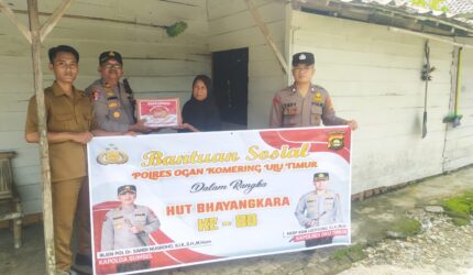 Kapolsek Buay Madang Timur, IPTU Swisspo, (kedua dari kiri), menyerahkan secara simbolis bantuan sembako kepada salah satu warga Desa Kumpul Rejo dalam rangka memperingati HUT Bhayangkara ke-80.