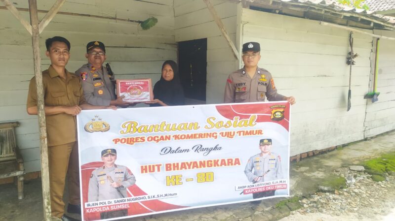 Kapolsek Buay Madang Timur, IPTU Swisspo, (kedua dari kiri), menyerahkan secara simbolis bantuan sembako kepada salah satu warga Desa Kumpul Rejo dalam rangka memperingati HUT Bhayangkara ke-80. 