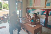 Bhabinkamtibmas Polsek Buay Madang Timur, Bripka Berlin Mandala (kiri), sedang berdialog dengan perangkat desa saat kegiatan sambang dan silaturahmi di Kantor Desa Metro Rejo, OKU Timur. 
