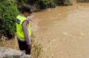 Anggota Piket Sabhara Polsek Buay Madang Timur, Aipda Sahrul Munir, memantau pergerakan arus dan debit air di aliran Sungai Macak, Desa Sukoharjo, Kecamatan Buay Madang Timur. 