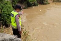 Anggota Piket Sabhara Polsek Buay Madang Timur, Aipda Sahrul Munir, memantau pergerakan arus dan debit air di aliran Sungai Macak, Desa Sukoharjo, Kecamatan Buay Madang Timur. 