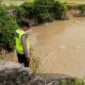 Anggota Piket Sabhara Polsek Buay Madang Timur, Aipda Sahrul Munir, memantau pergerakan arus dan debit air di aliran Sungai Macak, Desa Sukoharjo, Kecamatan Buay Madang Timur. 