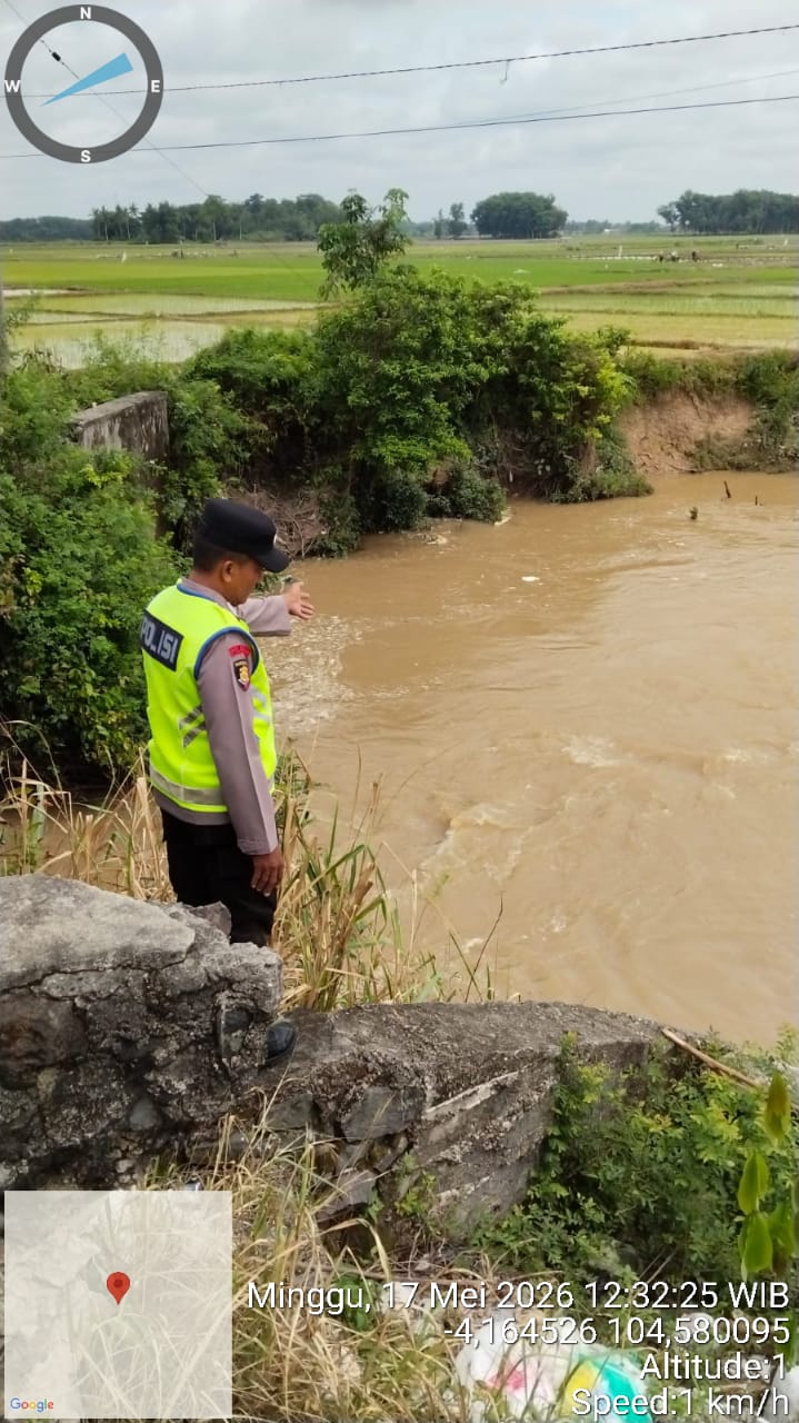 Anggota Piket Sabhara Polsek Buay Madang Timur, Aipda Sahrul Munir, memantau pergerakan arus dan debit air di aliran Sungai Macak, Desa Sukoharjo, Kecamatan Buay Madang Timur. 