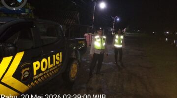Personel Polsek Buay Madang Timur berdiri di samping mobil dinas patroli saat melaksanakan Kegiatan Rutin Yang Ditingkatkan (KRYD) di Jalan Desa Kedung Rejo, Kecamatan Buay Madang Timur, Kabupaten OKU Timur, Sumatera Selatan. 