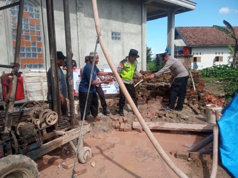Kapolsek Buay Madang Timur Iptu Swisspo, (kanan) memindahkan material batu bata bersama warga dan Takmir Masjid Al Amin saat meninjau pembangunan sumur bor dan MCK di Desa Berasan Mulya, Kecamatan Buay Madang Timur, Kabupaten OKU Timur. 