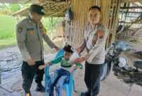 Bhabinkamtibmas Polsek Buay Madang Timur Bripka Nur Holik (kiri) bersama Brigadir Tedy Heryadi (kanan) menyerahkan paket daging kurban dari Kapolres OKU Timur kepada salah satu anak penyandang disabilitas di Desa Pengandonan, Kecamatan Buay Madang Timur, Kabupaten OKU Timur, Sumatera Selatan. 