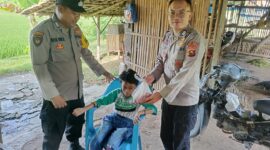 Bhabinkamtibmas Polsek Buay Madang Timur Bripka Nur Holik (kiri) bersama Brigadir Tedy Heryadi (kanan) menyerahkan paket daging kurban dari Kapolres OKU Timur kepada salah satu anak penyandang disabilitas di Desa Pengandonan, Kecamatan Buay Madang Timur, Kabupaten OKU Timur, Sumatera Selatan. 