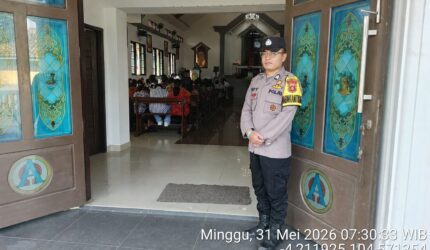 Anggota Polsek Buay Madang Timur, Brigadir Tedy Heryadi, berjaga di pintu masuk Gereja Trinitas Bangun Sari BK 3, Kecamatan Buay Madang Timur, Kabupaten OKU Timur.