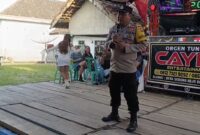 Bhabinkamtibmas Polsek Buay Madang Timur Bripka Nur Holik menyampaikan imbauan kamtibmas di atas panggung orgen tunggal saat menggelar operasi penertiban di Desa Gumuk Rejo, Kecamatan Buay Madang Timur, Kabupaten OKU Timur, Sumatera Selatan. 