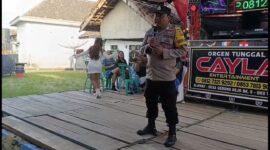Bhabinkamtibmas Polsek Buay Madang Timur Bripka Nur Holik menyampaikan imbauan kamtibmas di atas panggung orgen tunggal saat menggelar operasi penertiban di Desa Gumuk Rejo, Kecamatan Buay Madang Timur, Kabupaten OKU Timur, Sumatera Selatan. 