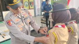 Kapolsek Buay Madang Timur, Iptu Swisspo, menyematkan tanda anggota kepada perwakilan Pramuka dalam Upacara Pelantikan Anggota Saka Bhayangkara Angkatan X di Mako Polsek Buay Madang Timur, Kabupaten OKU Timur. 