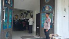 Personel Polsek Buay Madang Timur berjaga di depan pintu masuk Gereja Trinitas Bangun Sari BK 3, Kecamatan Buay Madang Timur, Kabupaten OKU Timur. 