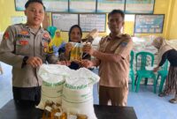  Polsek Buay Madang Timur Bripda Dekya Kevin Titara (kiri) bersama perangkat Desa Tambak Boyo (kanan) menyerahkan bantuan sosial berupa beras dan minyak goreng secara simbolis kepada salah satu warga penerima manfaat di Desa Tambak Boyo, Kecamatan Buay Madang Timur, Kabupaten OKU Timur. 