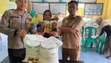  Polsek Buay Madang Timur Bripda Dekya Kevin Titara (kiri) bersama perangkat Desa Tambak Boyo (kanan) menyerahkan bantuan sosial berupa beras dan minyak goreng secara simbolis kepada salah satu warga penerima manfaat di Desa Tambak Boyo, Kecamatan Buay Madang Timur, Kabupaten OKU Timur. 