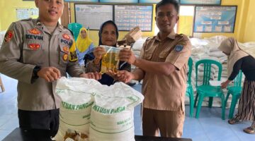  Polsek Buay Madang Timur Bripda Dekya Kevin Titara (kiri) bersama perangkat Desa Tambak Boyo (kanan) menyerahkan bantuan sosial berupa beras dan minyak goreng secara simbolis kepada salah satu warga penerima manfaat di Desa Tambak Boyo, Kecamatan Buay Madang Timur, Kabupaten OKU Timur. 