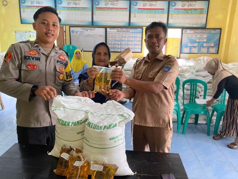  Polsek Buay Madang Timur Bripda Dekya Kevin Titara (kiri) bersama perangkat Desa Tambak Boyo (kanan) menyerahkan bantuan sosial berupa beras dan minyak goreng secara simbolis kepada salah satu warga penerima manfaat di Desa Tambak Boyo, Kecamatan Buay Madang Timur, Kabupaten OKU Timur. 