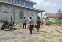 Kapolsek Buay Madang Timur IPTU Swisspo (tengah) memegang selang pembuangan air bersama personel Polsek saat meninjau langsung proses pengeboran sumur bor di samping Masjid Al-Amin, Desa Berasan Mulya, Kecamatan Buay Madang Timur, Kabupaten OKU Timur. 