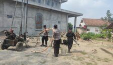 Kapolsek Buay Madang Timur IPTU Swisspo (tengah) memegang selang pembuangan air bersama personel Polsek saat meninjau langsung proses pengeboran sumur bor di samping Masjid Al-Amin, Desa Berasan Mulya, Kecamatan Buay Madang Timur, Kabupaten OKU Timur. 