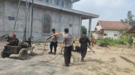 Kapolsek Buay Madang Timur IPTU Swisspo (tengah) memegang selang pembuangan air bersama personel Polsek saat meninjau langsung proses pengeboran sumur bor di samping Masjid Al-Amin, Desa Berasan Mulya, Kecamatan Buay Madang Timur, Kabupaten OKU Timur. 
