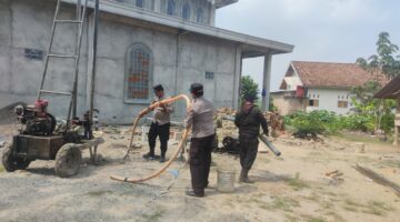 Kapolsek Buay Madang Timur IPTU Swisspo (tengah) memegang selang pembuangan air bersama personel Polsek saat meninjau langsung proses pengeboran sumur bor di samping Masjid Al-Amin, Desa Berasan Mulya, Kecamatan Buay Madang Timur, Kabupaten OKU Timur. 