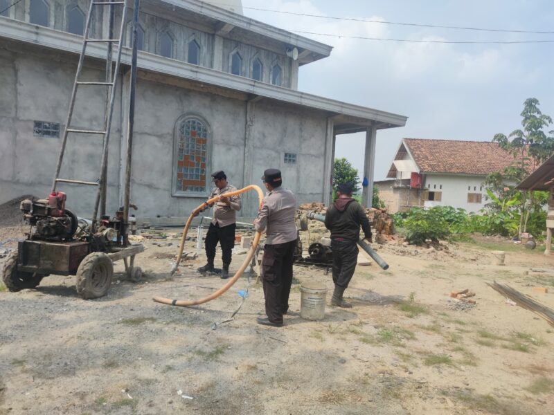 Kapolsek Buay Madang Timur IPTU Swisspo (tengah) memegang selang pembuangan air bersama personel Polsek saat meninjau langsung proses pengeboran sumur bor di samping Masjid Al-Amin, Desa Berasan Mulya, Kecamatan Buay Madang Timur, Kabupaten OKU Timur. 