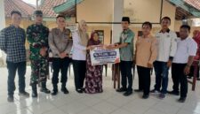 Kepala Desa Kedung Rejo, M Ahmad Asodikin (kelima kanan), menyerahkan bantuan secara simbolis kepada perwakilan warga lansia penerima manfaat disaksikan oleh Bhabinkamtibmas Polsek Buay Madang Timur Brigadir Tedy Heryadi (ketiga kiri) dan Babinsa Sertu Handoko (kedua kiri) di Balai Desa Kedung Rejo, Kecamatan Buay Madang Timur, Kabupaten OKU Timur.