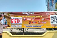 Kasium Polsek Buay Madang Timur Aipda Robbiansyah (kiri) meninjau hasil pemasangan banner sosialisasi "Layanan Kepolisian 110" di area Mako Polsek Buay Madang Timur, Kabupaten OKU Timur, Sumatera Selatan. 