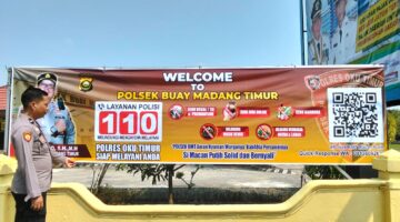 Kasium Polsek Buay Madang Timur Aipda Robbiansyah (kiri) meninjau hasil pemasangan banner sosialisasi 