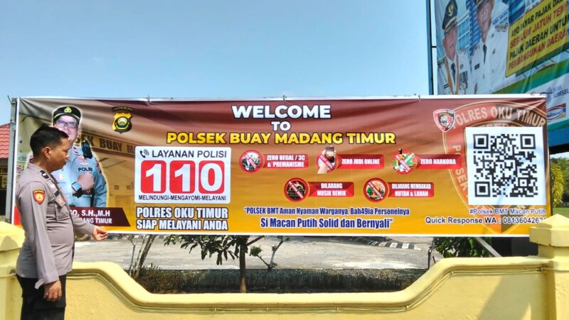 Kasium Polsek Buay Madang Timur Aipda Robbiansyah (kiri) meninjau hasil pemasangan banner sosialisasi 