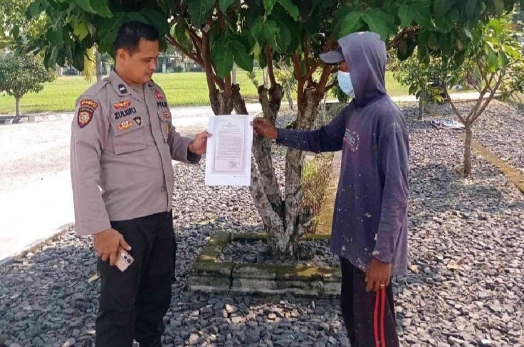 Personel Polsek Buay Madang Timur Aipda Zulkifli (kiri) menunjukan lembar Maklumat Kapolda Sumsel tentang larangan membakar hutan dan lahan kepada seorang warga di Desa Karang Tengah, Kecamatan Buay Madang Timur, Kabupaten OKU Timur, Sumatera Selatan. 