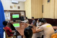 Jajaran personel Polsek Buay Madang Timur bersama warga sekitar membaur menyaksikan siaran langsung pertandingan babak penyisihan Piala Dunia 2026 antara Qatar vs Swiss di ruang pertemuan Mako Polsek Buay Madang Timur, Kabupaten OKU Timur, Sumatra Selatan. 