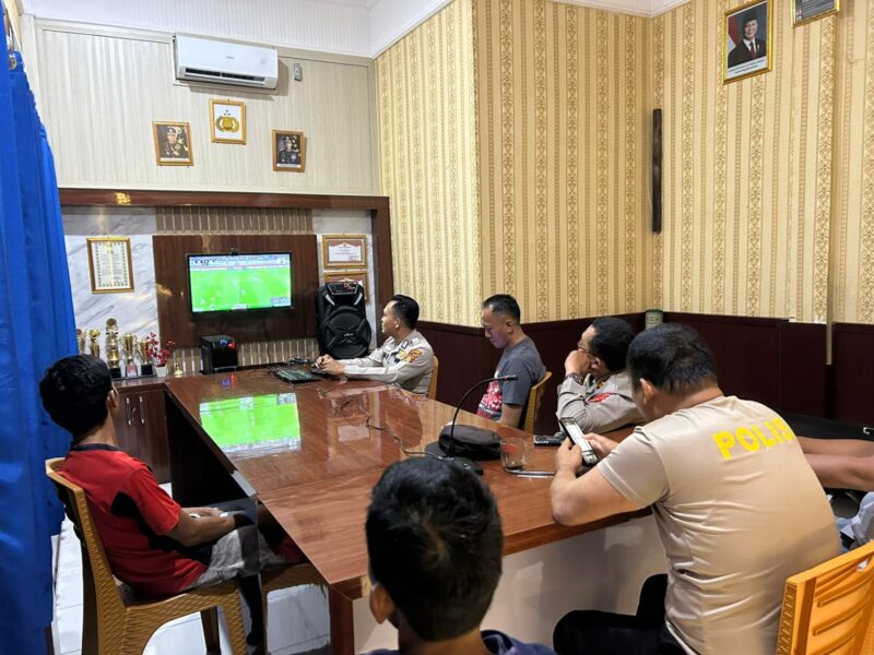 Jajaran personel Polsek Buay Madang Timur bersama warga sekitar membaur menyaksikan siaran langsung pertandingan babak penyisihan Piala Dunia 2026 antara Qatar vs Swiss di ruang pertemuan Mako Polsek Buay Madang Timur, Kabupaten OKU Timur, Sumatra Selatan. 