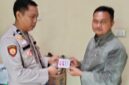 Kasium Polsek Buay Madang Timur AIPDA Robbiansyah (kiri) memberikan stiker informasi Layanan Kepolisian 110 kepada seorang warga di Mako Polsek Buay Madang Timur, Kabupaten OKU Timur. 