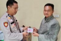 Kasium Polsek Buay Madang Timur AIPDA Robbiansyah (kiri) memberikan stiker informasi Layanan Kepolisian 110 kepada seorang warga di Mako Polsek Buay Madang Timur, Kabupaten OKU Timur. 