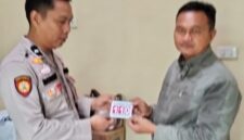 Kasium Polsek Buay Madang Timur AIPDA Robbiansyah (kiri) memberikan stiker informasi Layanan Kepolisian 110 kepada seorang warga di Mako Polsek Buay Madang Timur, Kabupaten OKU Timur. 