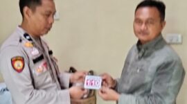 Kasium Polsek Buay Madang Timur AIPDA Robbiansyah (kiri) memberikan stiker informasi Layanan Kepolisian 110 kepada seorang warga di Mako Polsek Buay Madang Timur, Kabupaten OKU Timur. 