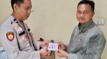 Kasium Polsek Buay Madang Timur AIPDA Robbiansyah (kiri) memberikan stiker informasi Layanan Kepolisian 110 kepada seorang warga di Mako Polsek Buay Madang Timur, Kabupaten OKU Timur. 