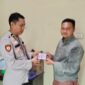 Kasium Polsek Buay Madang Timur AIPDA Robbiansyah (kiri) memberikan stiker informasi Layanan Kepolisian 110 kepada seorang warga di Mako Polsek Buay Madang Timur, Kabupaten OKU Timur. 