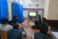 Personel Polsek Buay Madang Timur (BMT) bersama sejumlah masyarakat pencinta sepak bola menyaksikan siaran langsung pertandingan Pesta Bola Dunia 2026 antara Belgia melawan Mesir di ruang pertemuan Mako Polsek BMT, Kabupaten OKU Timur, Sumatra Selatan. 