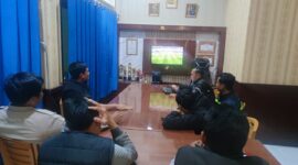 Personel Polsek Buay Madang Timur (BMT) bersama sejumlah masyarakat pencinta sepak bola menyaksikan siaran langsung pertandingan Pesta Bola Dunia 2026 antara Belgia melawan Mesir di ruang pertemuan Mako Polsek BMT, Kabupaten OKU Timur, Sumatra Selatan. 