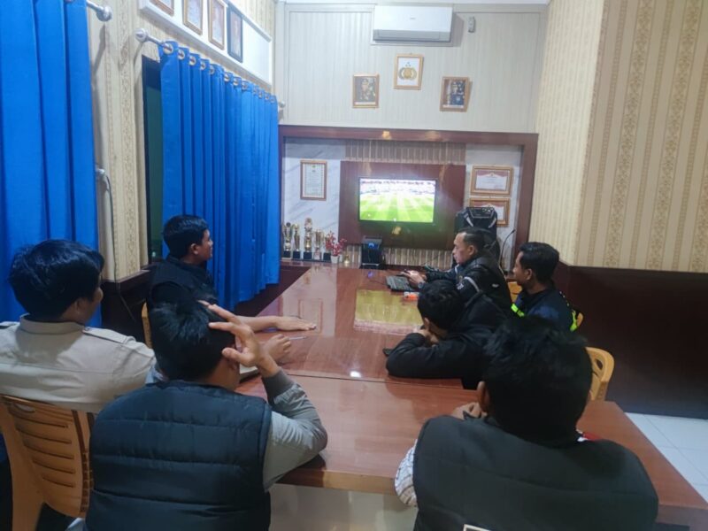 Personel Polsek Buay Madang Timur (BMT) bersama sejumlah masyarakat pencinta sepak bola menyaksikan siaran langsung pertandingan Pesta Bola Dunia 2026 antara Belgia melawan Mesir di ruang pertemuan Mako Polsek BMT, Kabupaten OKU Timur, Sumatra Selatan. 