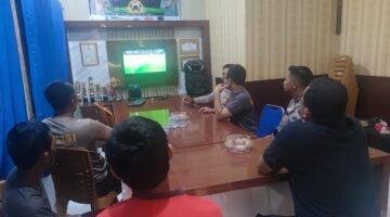 Kapolsek Buay Madang Timur Iptu Swisspo, bersama personel dan warga pencinta sepak bola saat menyaksikan pertandingan Pesta Bola Dunia 2026 antara Swiss vs Bosnia di ruang pertemuan Mako Polsek Buay Madang Timur, OKU Timur. 